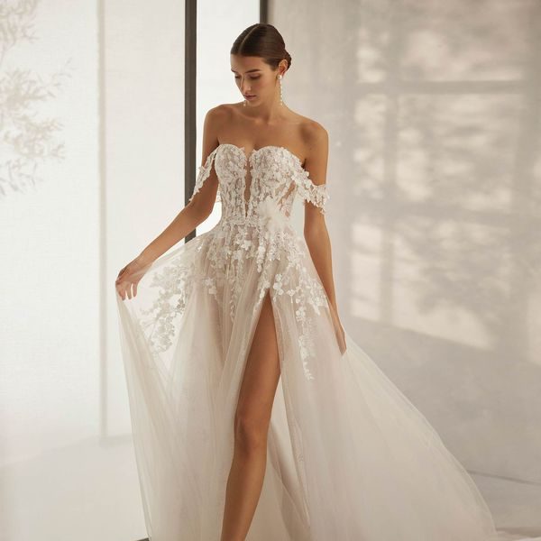 A-Linien ab 1300,-€ Braut in einem schulterfreien, blütenverzierten A-Linien Kleid mit hoher Spaltung.